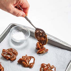 Spooning pecan praline mixture onto parchment-lined baking sheet