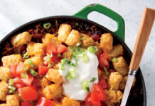 Baked Beef and Bean Tater Tot Casserole Ground beef and bean tater tot casserole baked in a skillet topped with tomatoes, green onion, and sour cream.